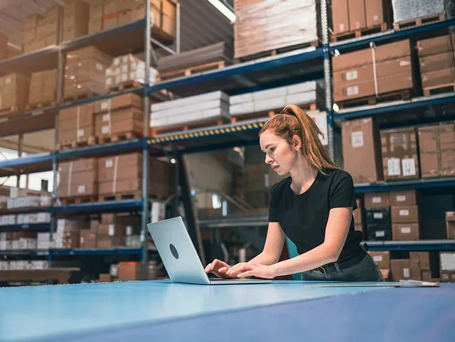 Mitarbeiterin im E-Commerce Fulfillment für Wien im Lager am Laptop
